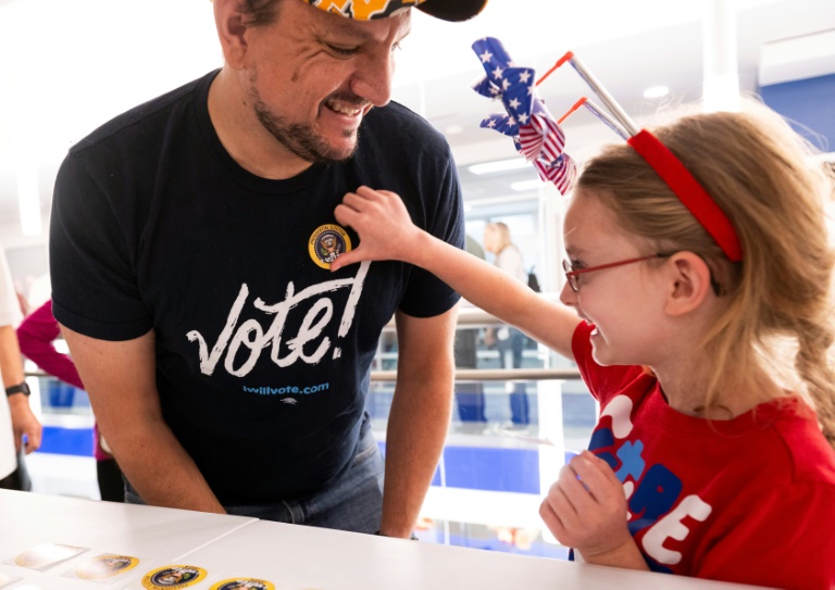 https://d.ibtimes.com/en/full/4549435/nick-vucic-gets-i-voted-sticker-his-daughter-abigail-7-after-he-casts-his-early-vote.jpg