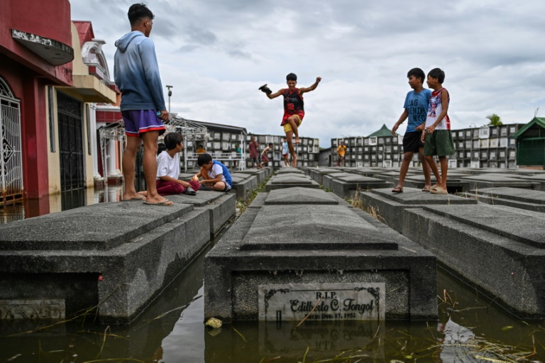 https://d.ibtimes.com/en/full/4558332/people-jump-tombs-they-visit-submerged-cemetery-philippines-pampanga-province.jpg