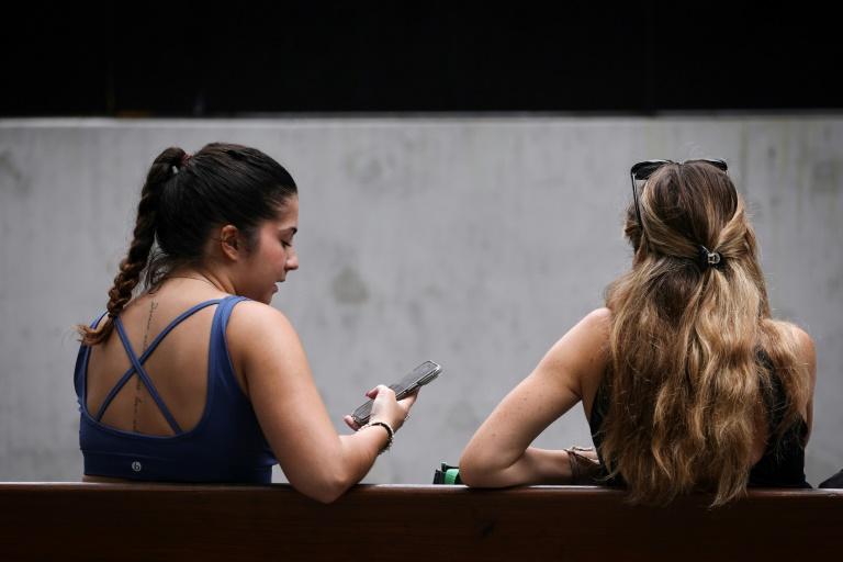 https://d.ibtimes.com/en/full/4564413/two-women-sit-bench-looking-their-phone-central-sydney-australian-government-says-new-law.jpg