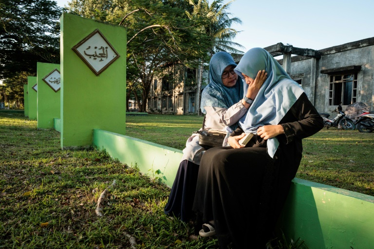 https://d.ibtimes.com/en/full/4571537/woman-comforts-her-daughter-after-prayers-mass-grave-indonesias-aceh.jpg