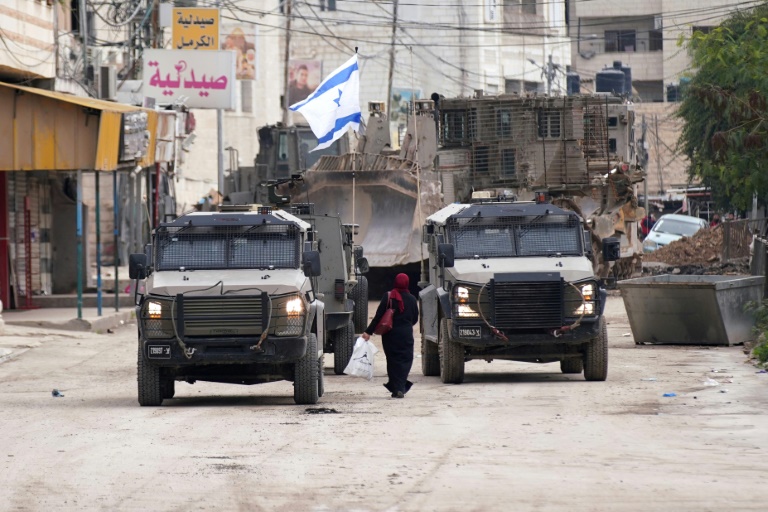 https://d.ibtimes.com/en/full/4577322/palestinian-woman-walks-past-israeli-army-vehicles-during-military-raid-jenin-occupied-west.jpg