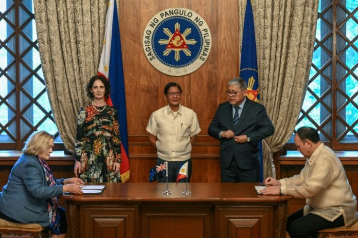 New Zealand Defence Minister Judith Collins (L) and Philippine Defence Secretary Gilberto Teodoro (R) sign a visiting forces pact on Wednesday as President Ferdinand Marcos (C) looks on