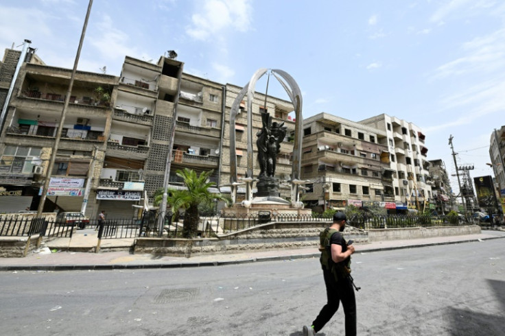 An armed man walks through the mostly Druze and Christian Damascus suburb of Jaramana, which came under attack by Islamists this week