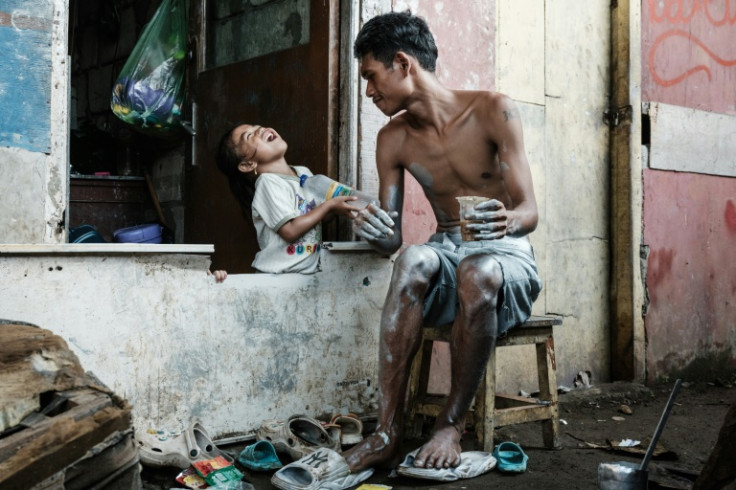 Keris Munandar plays with his daughter Nimas Apriyani before painting his body silver in front of his home in Jakarta