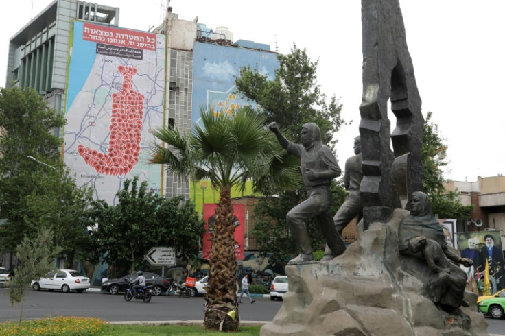 People drive past an anti-Israel billboard in Tehran's Palestine square on May 5, 2025