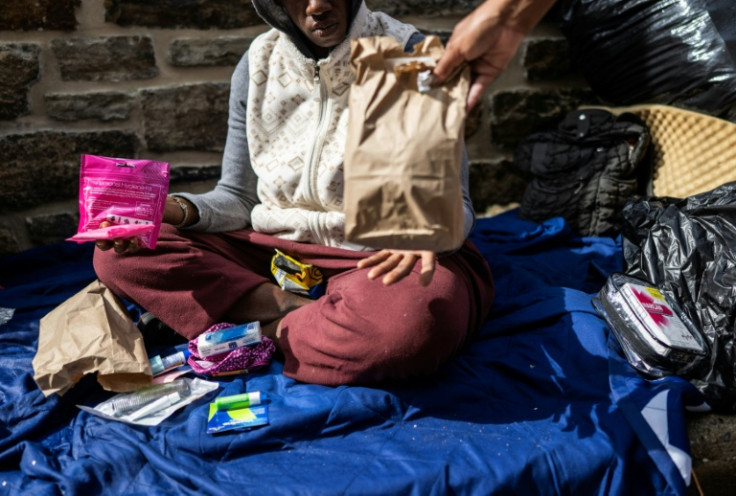 Genese Hubbard, a Peer Recover Coach at Our Daily Bread Employment Center (ODBC) with the Catholic Charities, hands out supplies and Narcan to an unhoused women living in an alley in Baltimore, Maryland on June 10, 2025
