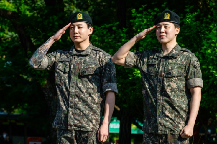BTS members Jungkook (L) and Jimin (R) salute after their release from South Korean mandatory military service