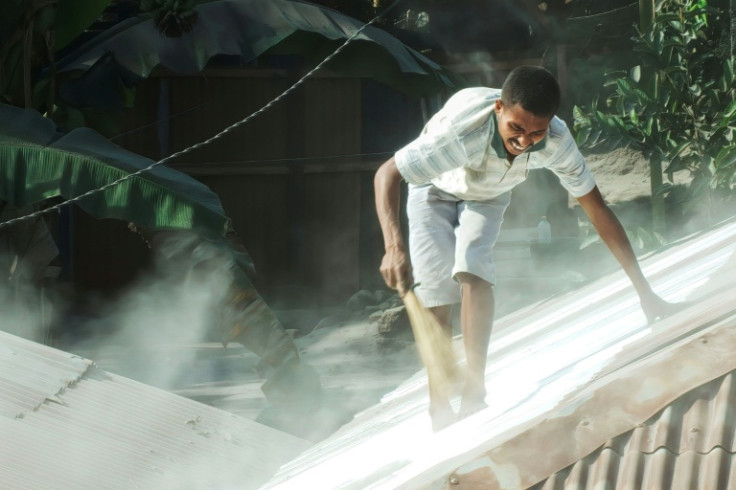 A villager cleans the roof of his home from volcanic ash a day after Mount Lewotobi Laki-Laki erupted