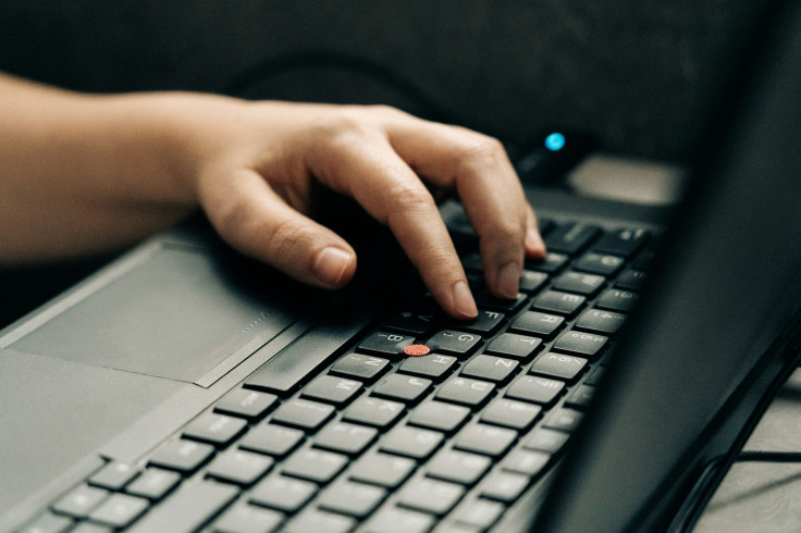 Close-up of a person’s hand typing on a laptop keyboard