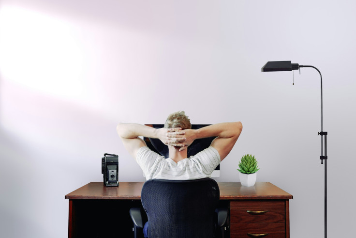 Man sitting at desk with hands behind head