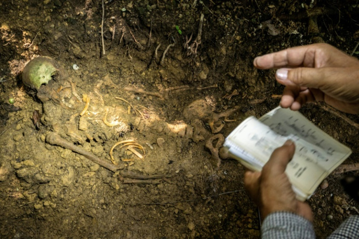 Takamatsu Gushiken, a volunteer who recovers the remains of war dead to be reunited with their families, points at the skeletal remains of a person who died in the Battle of Okinawa during World War II, at a forest in Itoman