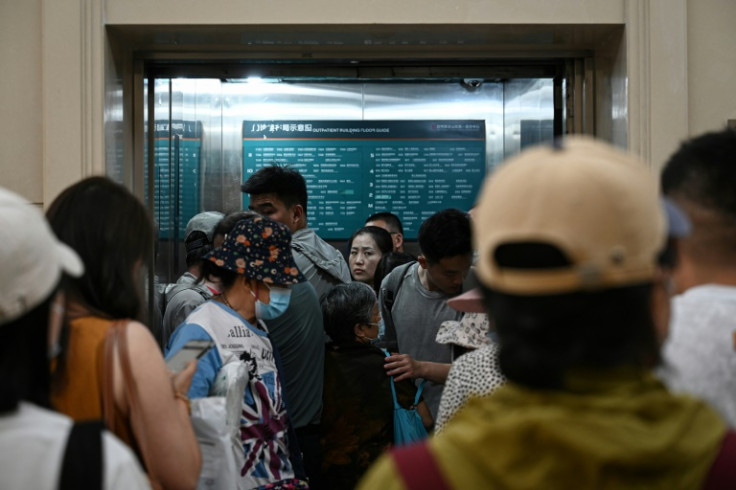 People wait to take a crowded elevator at a hospital in Beijing