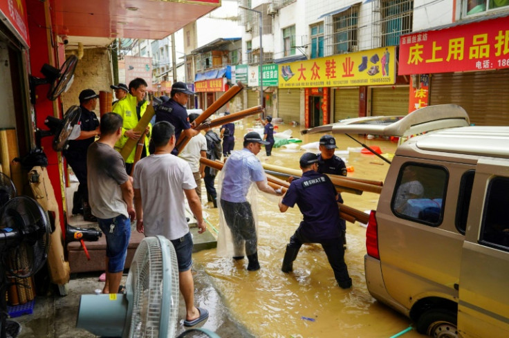 SWAT team members help shop owners remove equipment in a flooded street in Congjiang, in China's southwest Guizhou region