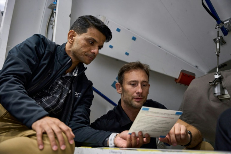 Ax-4 crew members reviewing a procedure checklist card during training within the ISS Harmony module mockup