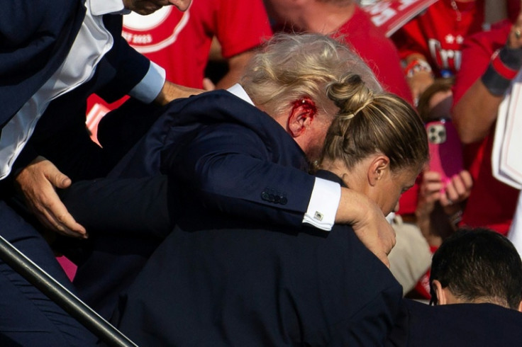 Then-US Republican candidate Donald Trump with blood on his ear, surrounded by Secret Service agents, after the assassination attempt in 2024