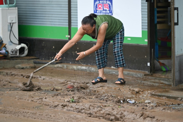 A woman removes mud in front of her store after flooding caused by record-breaking rains in Seosan