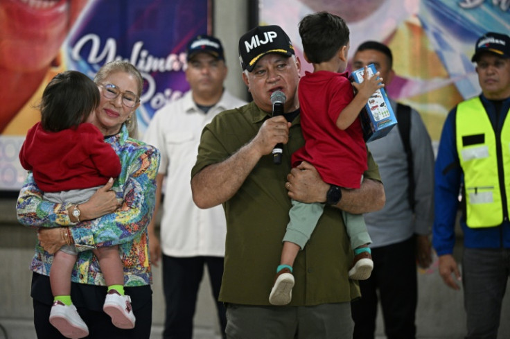 Venezuela's Interior Minister Diosdado Cabello carries one of the repatriated children