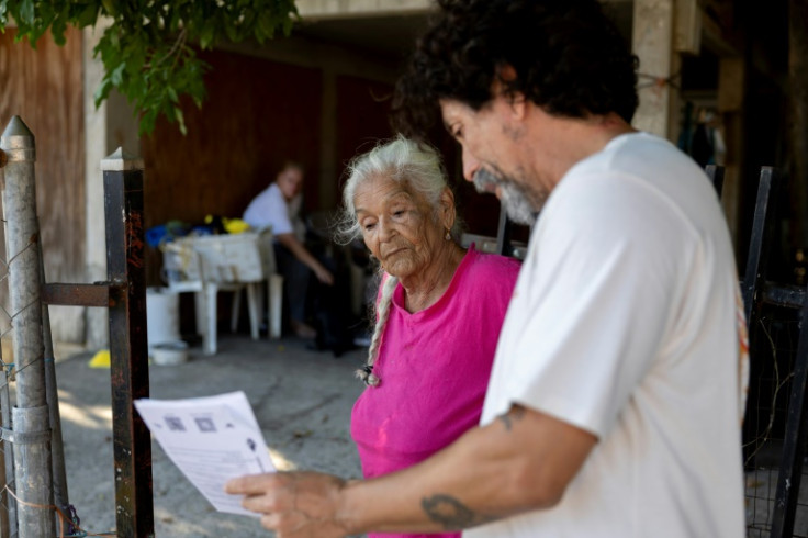 Braulio Quintero (R), who is with a coalition of groups opposing the construction of the mega project Esencia, talks to Mayra Perez Montalvo, 82, about how the project is going to affect the locals in Cabo Rojo