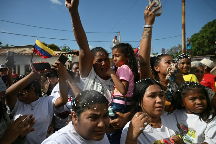 Mercedes Yamarte (C), mother of Mervin Yamarte, a Venezuelan migrant repatriated from a prison in El Salvador, reacts upon his arrival while holding Mervin's daughter in her arms