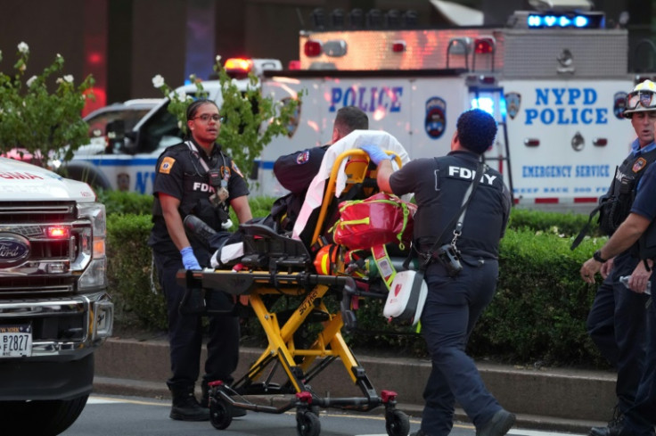 Firefighters wheel a police officer on a gurney as police respond to an incident in the Midtown Manhattan neighborhood of New York
