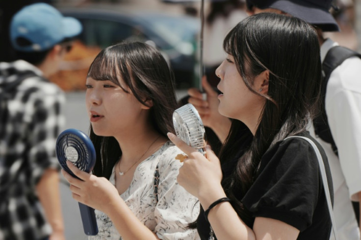 Pedestrians use battery-powered fans to cool themselves in Tokyo