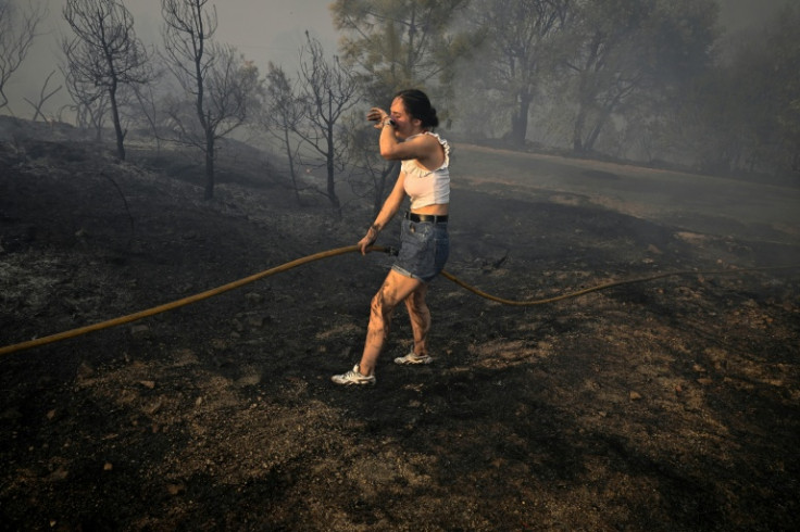A woman tries to extinguish a wildfire near the village of Larouco in northwestern Spain on August 13, 2025