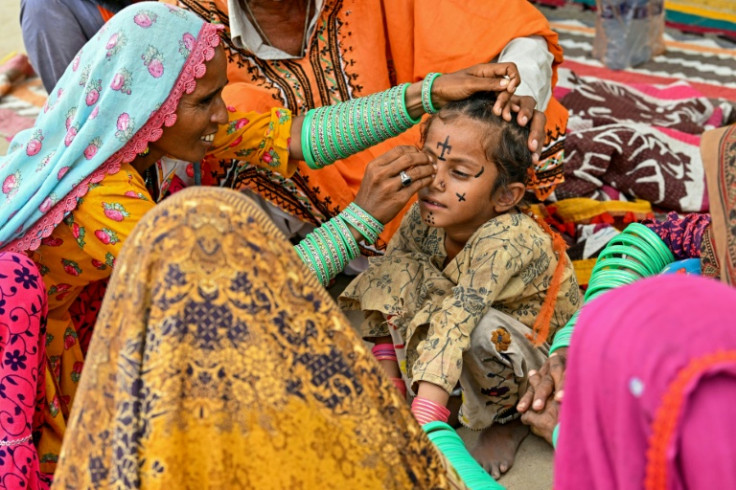 Artist Guddi Manthar inks a tattoo onto the face of seven-year-old Champa