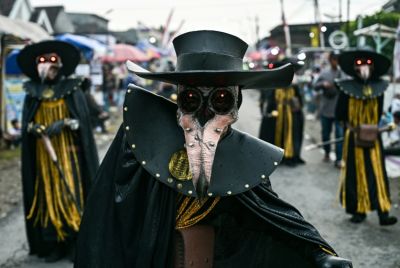 Costumed dancers perform as they follow a truck mounted with a tower of subwoofers and spotlights during a "sound horeg"