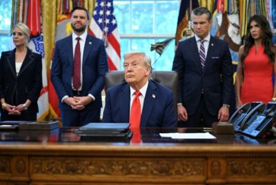 US President Donald Trump speaks to the press in the Oval Office, surrounded by top aides