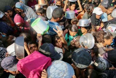 A Palestinian boy flashes the victory sign as he pushes through a crowd seeking a hot meal at a charity kitchen in the southern Gaza Strip