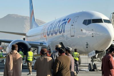 People stand on the tarmac next to a flydubai plane after it landed at Kabul airport in November 2023