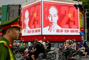 A police officer watches traffic under a billboard of Ho Chi Minh in Hanoid, a day before Vietnam's National Day