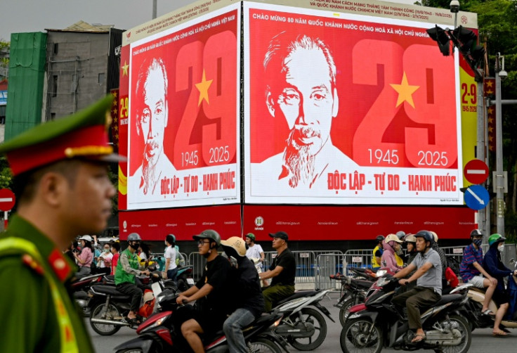 A police officer watches traffic under a billboard of Ho Chi Minh in Hanoid, a day before Vietnam's National Day