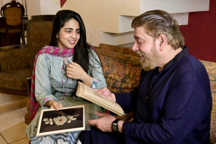 Khawaja Naim Murad (R), the great-grandson of Sir Salimullah Bahadur - the last prince or Nawab of Dhaka, shows ornament designs as he sits beside his daughter Nameera Naim during an interview with AFP at their house in Dhaka