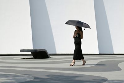 A woman holding an umbrella to shelter from the sun walks along a street in Beijing on June 23, 2025. Beijing residents sought shade and cooled off in canals on June 23 as the Chinese capital sweltered in its hottest day of the year so far.