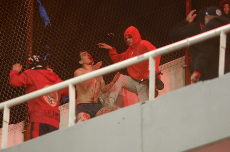 A fan of Universidad de Chile bleeds while being hit by fans of Independiente during the interruption of the Copa Sudamericana round of 16 second leg football match between Argentina's Independiente and Chile's Universidad de Chile at the Libertadores de