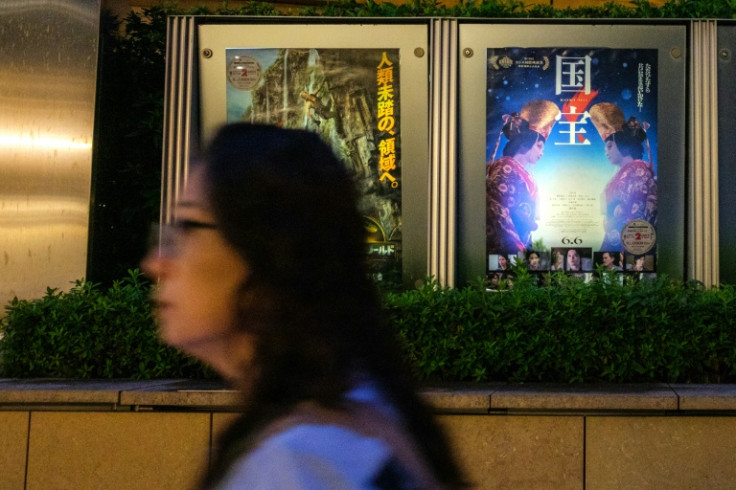 A woman walks past the poster of Japanese movie "Kokuho" (R) outside a cinema in Tokyo's Roppongi district on September 4, 2025. Lasting almost three hours, "Kokuho" is about two "onnagata", male players of female roles in kabuki, a rarefied form of class
