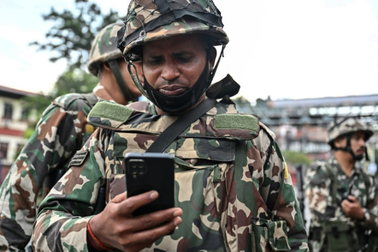 A soldier uses a mobile phone during a curfew imposed to restore law and order in Kathmandu on September 12, 2025. From sparking protests to giving young people a platform to discuss their country's political future, social media was key to Nepal's uprisi