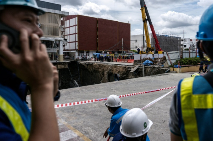 Dozens of police and city officials cordoned off the site, while a pickup truck teetered precariously on the edge of the hole