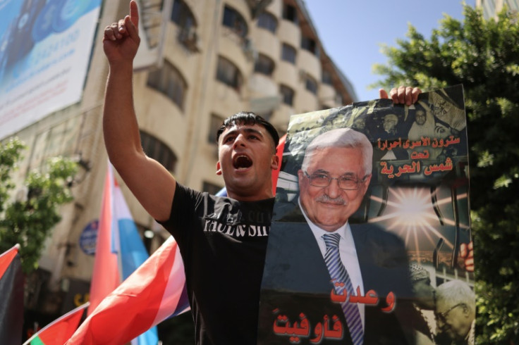 A Palestinian chants slogans in Ramallah while holding a portrait of Palestinian Authority president Mahmud Abbas