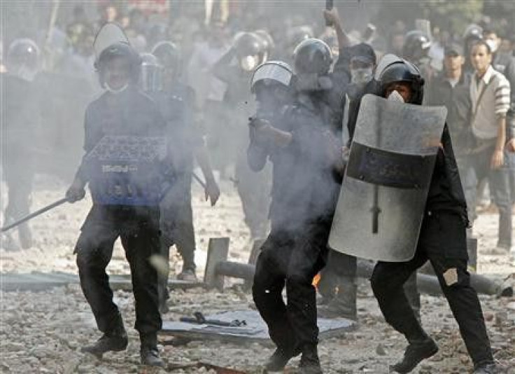 A riot policeman fires rubber bullets at protesters during clashes on a side street near Tahrir Square in Cairo
