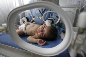 A nurse looks after a premature baby inside an incubator