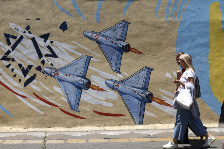Iranian women walk past an anti-US and anti-Israeli mural in