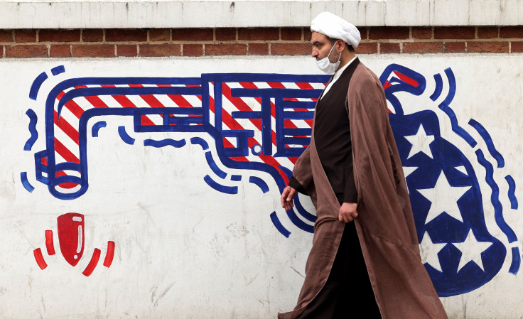 An Iranian cleric walks past an anti-US mural