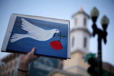 An demonstrator holds up a sign with a peace symbol