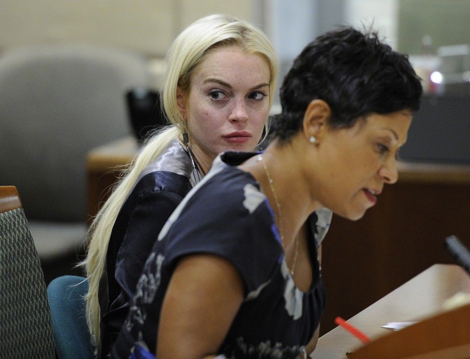 Actress Lindsay Lohan sits in court with her lawyer Shawn Chapman Holley, during a compliance check to report her progress on 480 hours of community service she must do for shoplifting a necklace from a Venice jeweler, in Los Angeles