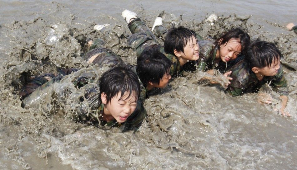 Elementary school students crawl forward at a mud flat as they participate in a summer military camp for civilians at the Cheongryong Self-denial Training Camp run by retired marines in Ansan