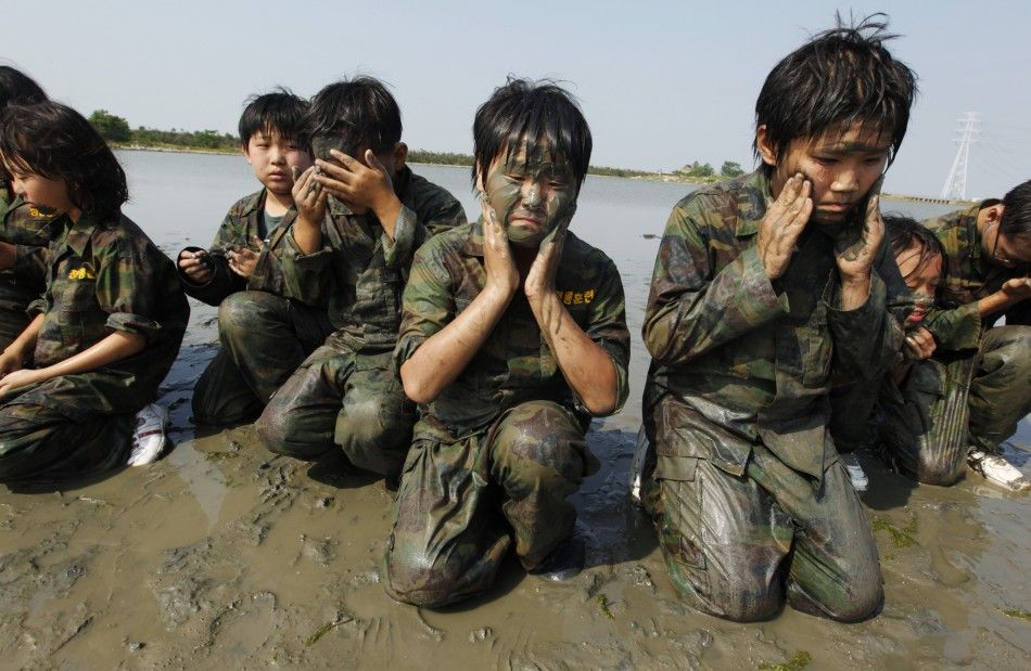 Elementary school students apply mud on their faces as they participate in a summer military camp at the Cheongryong Self-denial Training Camp in Ansan
