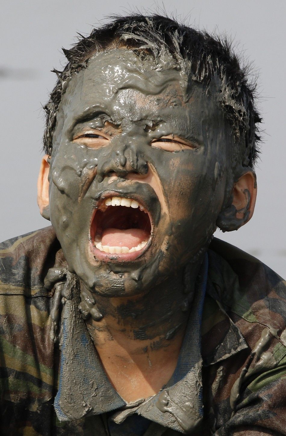 An elementary school student screams at a mud flat as they participate in a summer military camp for civilians at the Cheongryong Self-denial Training Camp run by retired marines in Ansan