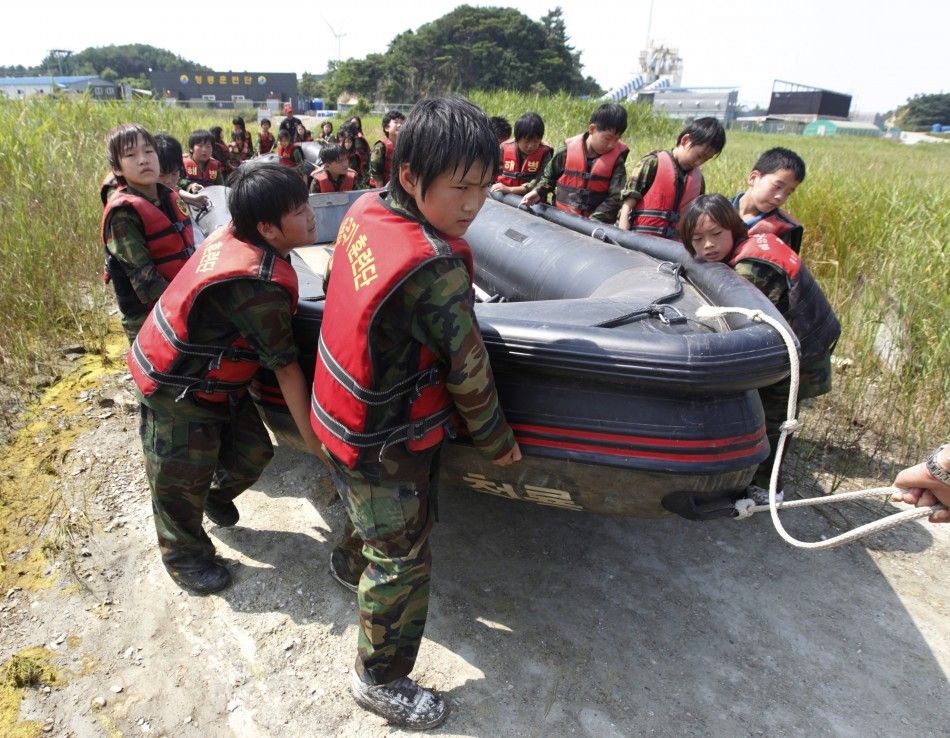 Elementary school students carry a rubber boat as they participate in a summer military camp at the Cheongryong Self-denial Training Camp in Ansan